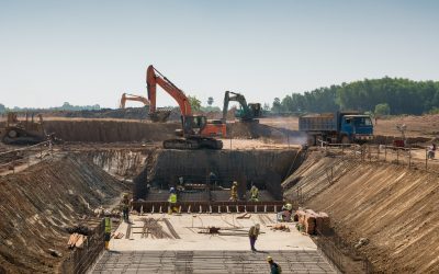 A close shot of heavy machines and construction workers working on a building